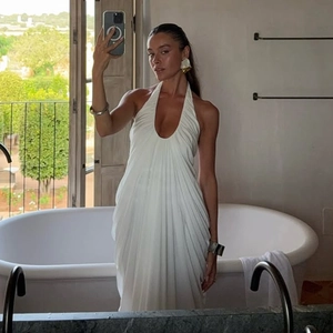 Mirror selfie showing white halter neck maxi dress with deep V-neck and pleated details