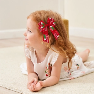 Barrette nœud de Noël rouge avec motif Père Noël porté par une petite fille sur le côté
