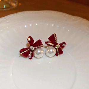 Dettaglio di orecchini a fiocco in velluto rosso con diamanti e perla su ceramica