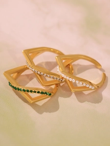 Detailed macro view of three gold stainless steel rings with green zircon and pearls