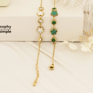 Detail of golden clover bracelets with shell inlay and green malachite on a white background