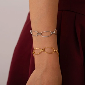 Minimalist geometric link bracelet in gold and silver finish on a dark red fabric