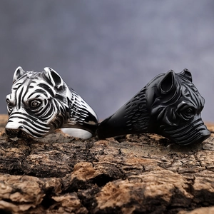 Detailed view of silver and black punk dog head rings on natural wood bark base