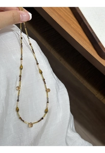 Detail of beaded necklace with gold metal tubes and champagne faceted crystal beads
