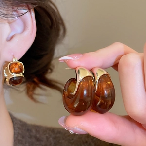 Detailed view of amber resin C-shaped earrings with elegant gold-tone metal trim