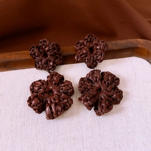Dettaglio macro di orecchini vintage a fiore intrecciato marrone con perle