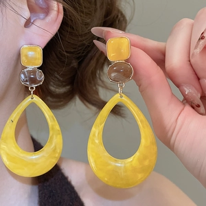 Detail of resin teardrop earrings with amber marble texture and gold metallic accents