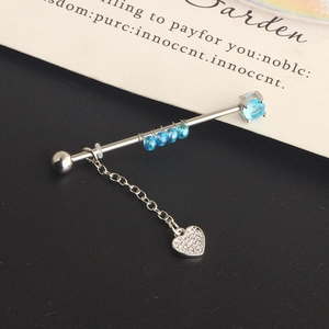 Detail view of steel industrial barbell with blue beads and dangling crystal heart charm