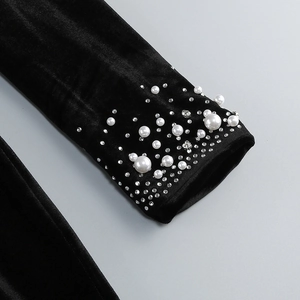 Detail view of black velvet sleeves decorated with white pearls and shiny rhinestones