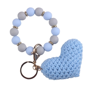 Detail of blue crochet heart keychain with blue and grey silicone beads on golden ring