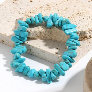 Macro detail of turquoise gemstone stretch bracelet with natural stone texture on stone slabs