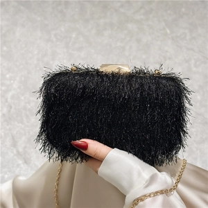 Macro detail of elegant black fringe evening clutch with gold metal clasp and chain