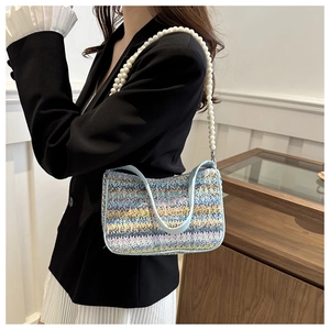 Détail du sac tricoté bleu clair avec bandoulière en perles et motif papillon