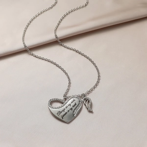 Detail of silver heart wing necklace with zircon and memorial engraving on satin