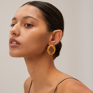 Close-up of model wearing chunky 18k gold plated stainless steel hollow oval hoop earrings