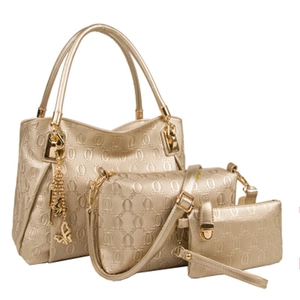 Detailed macro view of champagne gold three-piece bag set with embossed chain pattern