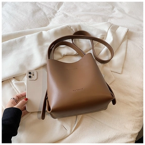 Detailed close-up of brown leather bucket bag on white fabric with fashion accessories