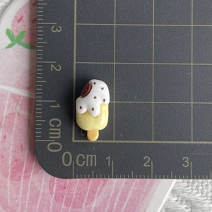 Close-up of yellow and white resin popsicle charm with bite mark and cookie detail
