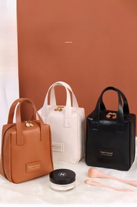 Detailed view of the dual-way metal zippers and matte cream leather on a cosmetic bag