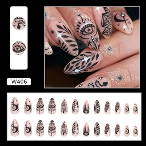 Detailed view of stiletto press-on nails with nude pink base and black mystical patterns