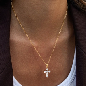 Dettaglio di una collana in acciaio dorato con ciondolo a croce in zircone su modella