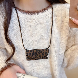 Close-up of leopard print leather mini bag necklace worn over a white knit sweater