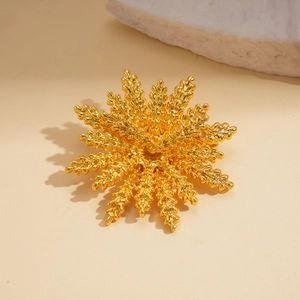 Macro detail of golden wheat flower brooch showing matte texture and layered leaf design
