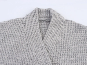 Macro shot of grey cashmere knit cardigan detail showing V-neckline and waffle texture