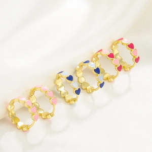 Golden heart-shaped chain rings with colorful enamel inlay on white silk background
