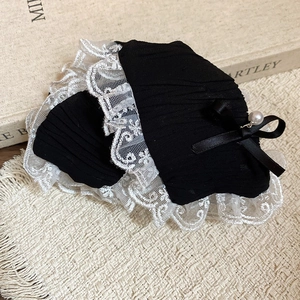 Detail of black pleated wrist cuffs with white lace trim, ribbons, and tiny pearls