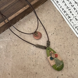 Close-up of bohemian water drop pendant necklace with vintage buttons and tassel detail