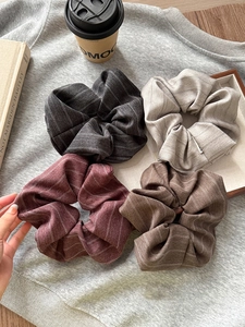 Close-up of four striped fabric scrunchies in grey, beige, burgundy and brown colors