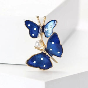 Detail of blue enamel butterflies brooch with gold plating and white pearl accent