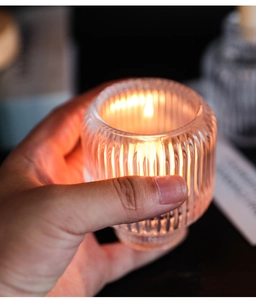 Detailed view of hand-held ribbed glass candle holder with warm glowing flame
