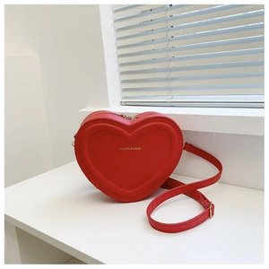 Dettaglio della borsa a tracolla rossa a forma di cuore con goffratura su un davanzale