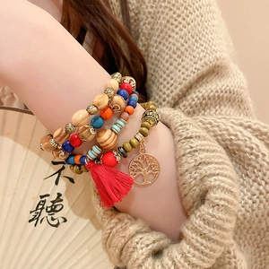 Detail of bohemian multilayer sandalwood beaded bracelet with red tassel and life tree charm
