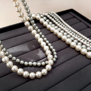 Detailed close-up of 2mm crystal pearl necklaces in white and silver grey on jewelry tray