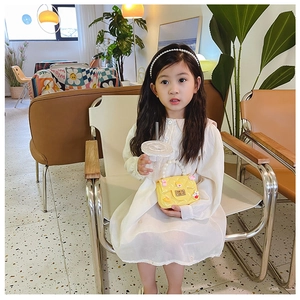 Toddler girl modeling a yellow pearl handle crossbody bag with a white long sleeve dress