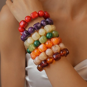 Detailed close-up of stacked colorful acrylic beaded bracelets with square and round beads