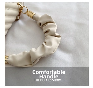 Close-up of beige quilted handbag featuring a ruched scrunchie handle and gold hardware