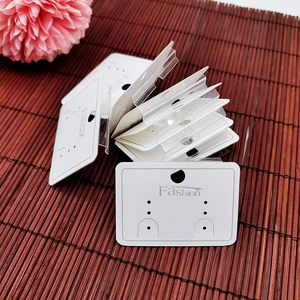 Close-up of white PVC earring display cards with Fashion text on a bamboo mat