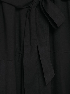 Detailed close-up of the black woven fabric texture and tied waist bow on the dress