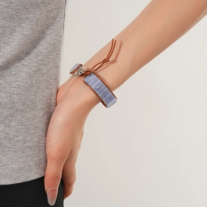 Dettaglio delle perle in pietra blu e chiusura a girasole su bracciale in pelle intrecciata