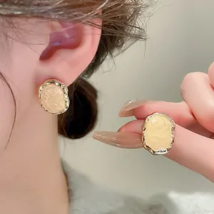 Détails rapprochés de boucles d'oreilles rétro dorées avec centre en émail crème