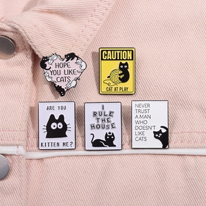 Détail de pin's chat noir en émail portés sur une veste en jean rose