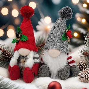 Red and grey Christmas gnome dolls made of knitted fabric on a snowy winter background