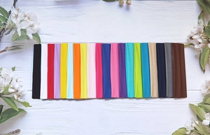 Wide range of colorful elastic yoga headbands in various solid colors on wooden background