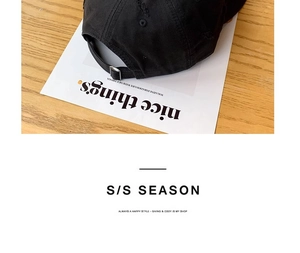 Detail view of the adjustable metal buckle on the back of this black cotton baseball cap