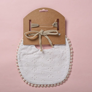 Détail du bavoir en dentelle blanche et bandeau à nœud kaki sur carte de présentation