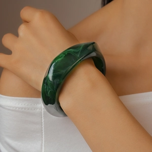 Detail of wide resin bangle with green marble ink texture on model's wrist